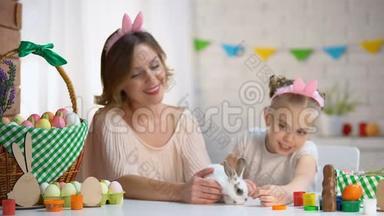 小女孩在妈妈手里玩<strong>可爱</strong>的<strong>小兔子</strong>，宠物，复活节的象征
